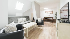Ein modernes Wohnzimmer mit einer Couch, einem Couchtisch, einem Sessel und einem Fernseher.
