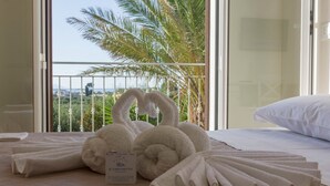 A hotel room with a bed, a sign indicating room service availability, and a view of palm trees through a balcony. - Baglio il Giovinetto (Marsala)