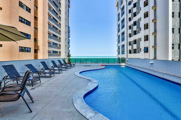 A swimming pool with lounge chairs and a view of a building.