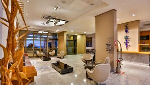 A hotel lobby with a seating area, a reception desk, and a large window offering a view. - Flat Beach Class Executive (Recife)