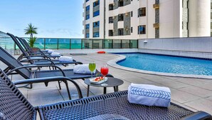 A rooftop pool area with lounge chairs, a pool, and a view of the ocean. - Flat Beach Class Executive (Recife)