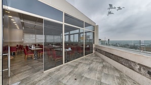 A modern building with large glass windows and a terrace with red chairs and tables. - Marcello Hotel (Istanbul)