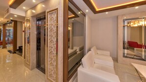 A modern hotel lobby with a glass partition, a white sofa, and a reception desk. - Marcello Hotel (Istanbul)