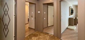A hotel corridor with wooden flooring, beige walls, and doors with geometric designs. - Marcello Hotel (Istanbul)