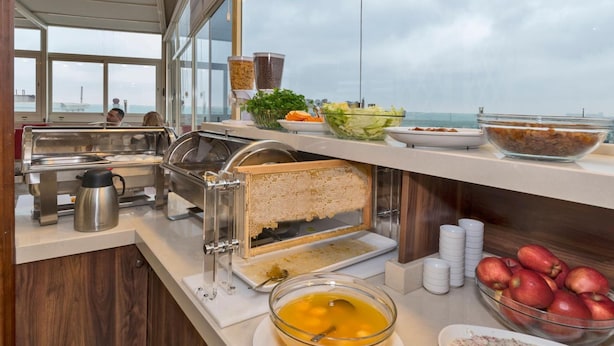 A buffet setup with various food items, a sandwich maker, and a view of the sea. - Marcello Hotel (Istanbul)