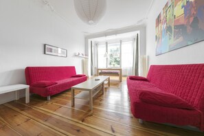 A room with two red sofas, a white bench, and a wooden coffee table.