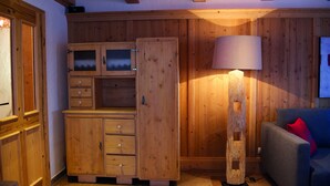 A wooden-paneled room with a cabinet, a lamp, and a sofa.