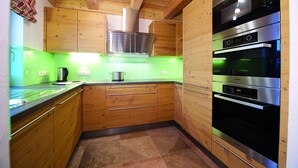 A modern kitchen with wooden cabinets, stainless steel appliances, and a green backsplash.