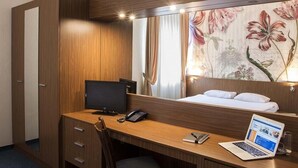 A hotel room with a wooden desk, a laptop, a telephone, and a bed with white linens. - Hotel Diter (Sofia)