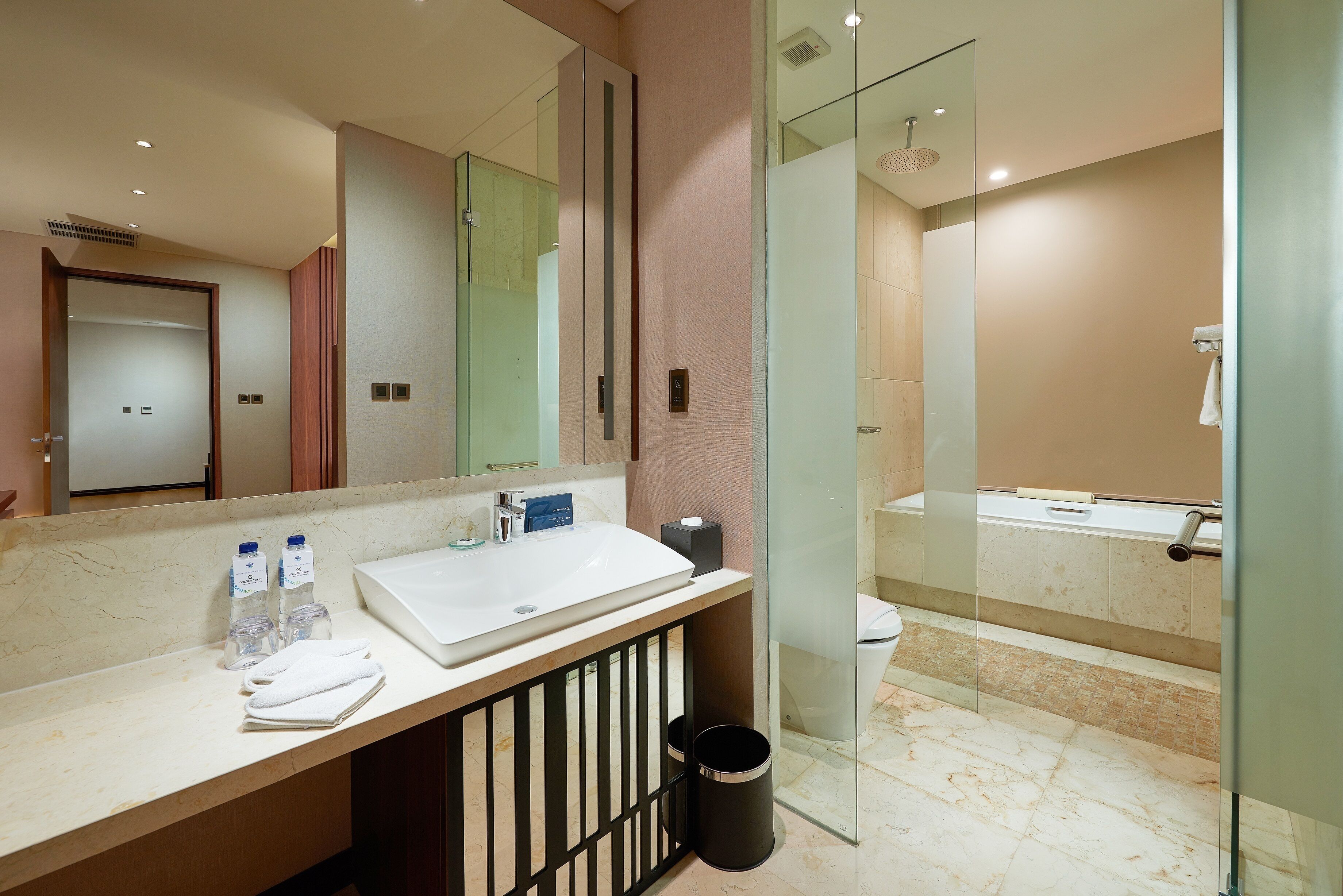 A modern bathroom with a large mirror, a white sink, and a glass-enclosed shower.