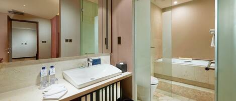 A modern bathroom with a large mirror, a white sink, and a glass-enclosed shower.