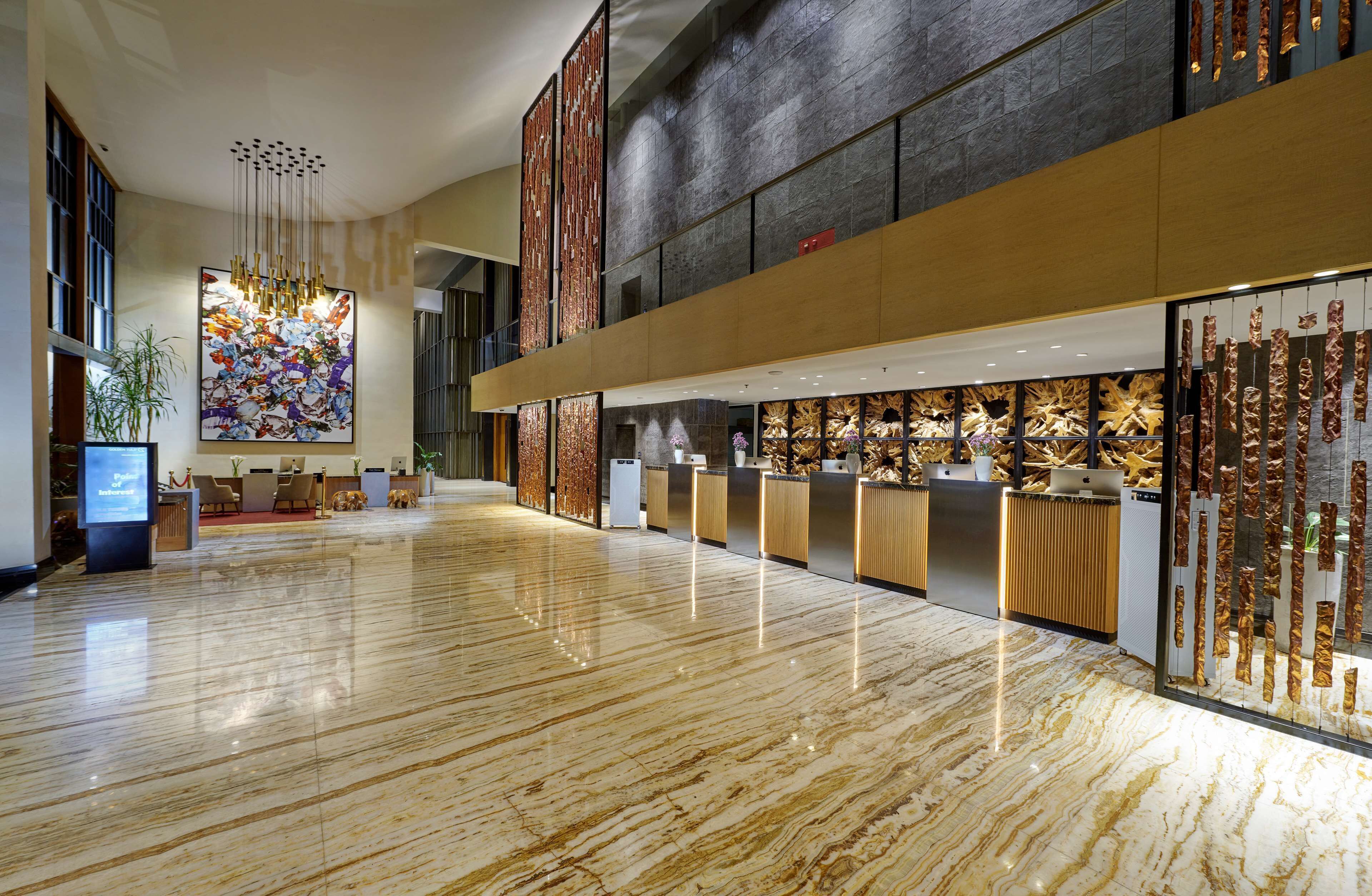A spacious lobby with a polished marble floor, a reception desk, and a large abstract painting.