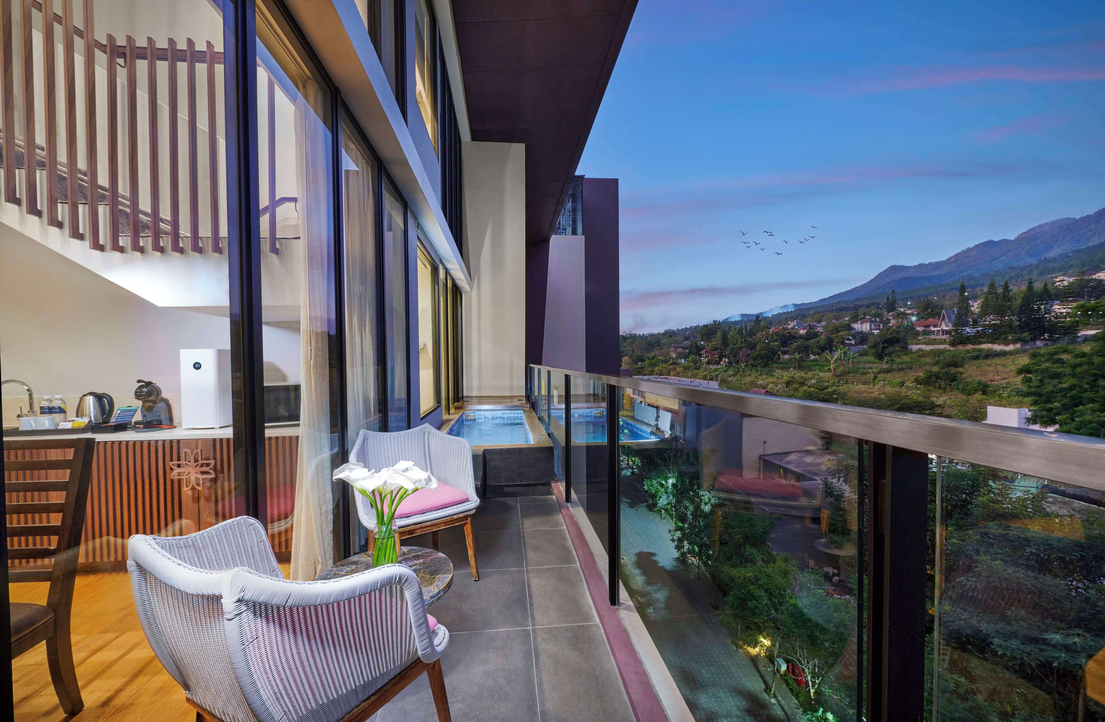 Un balcón con vistas a un paisaje montañoso, una zona de estar con mesa y sillas, y una decoración interior moderna.