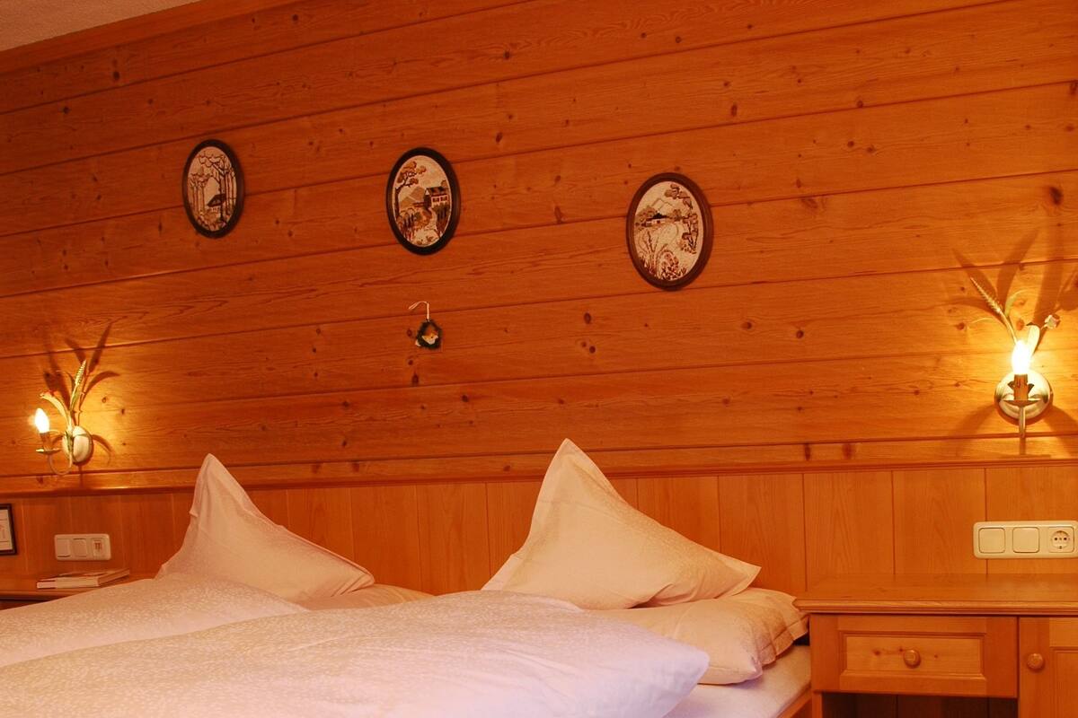 Un dormitorio con paneles de madera, una cama, mesitas de noche y lámparas fijadas a la pared.