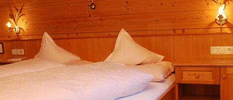 A wooden-paneled bedroom with a bed, nightstands, and wall-mounted lamps.