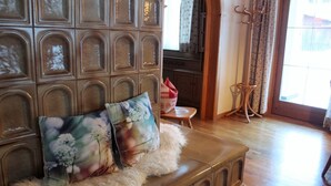 A cozy room with a wooden bench, floral cushions, and a decorative wall panel. - Ferienwohnung Ahnenhöfl (Gaschurn)