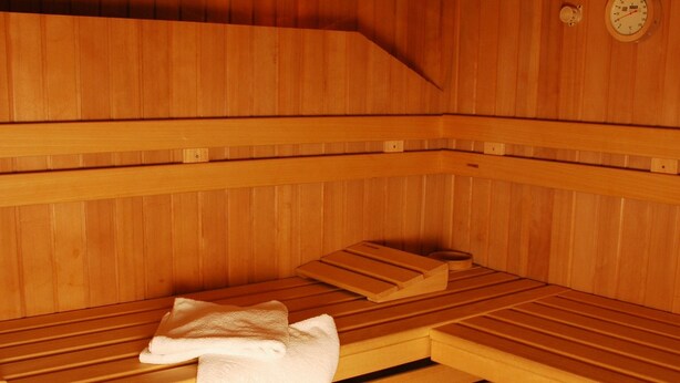 A sauna with wooden benches, a towel, and a wooden bucket. - Ferienwohnung Ahnenhöfl (Gaschurn)