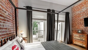 A bedroom with a large bed, a wooden dresser, and a view of the outdoors through a sliding glass door. - Well Well Aparthotel (Kraków)