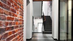 A hallway with a brick wall, a star-patterned floor, and a staircase leading to another room. - Well Well Aparthotel (Kraków)