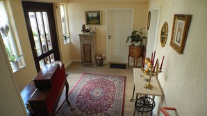 A hallway with a wooden bench, a red rug, a small table with candles, and a door.