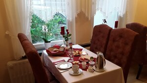 A dining table set with plates, glasses, and a pitcher, surrounded by red upholstered chairs.