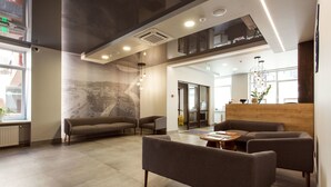 A modern lobby with sofas, a reception desk, and a large window.