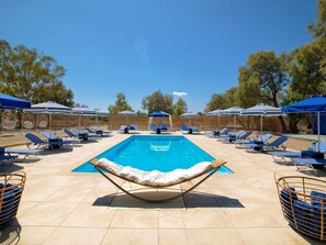 Zona de piscina con sillones de descanso y sombrillas.