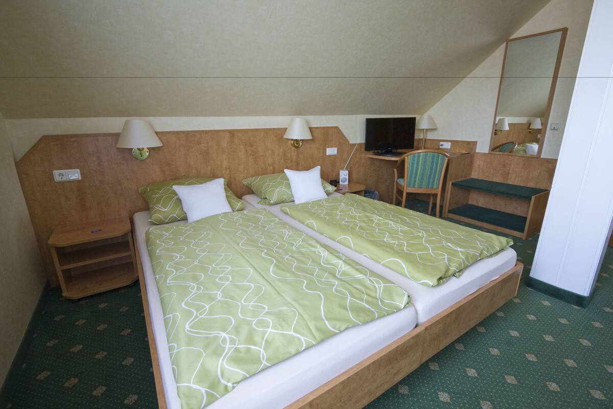 A hotel room with two beds, a television, a desk, and a chair.