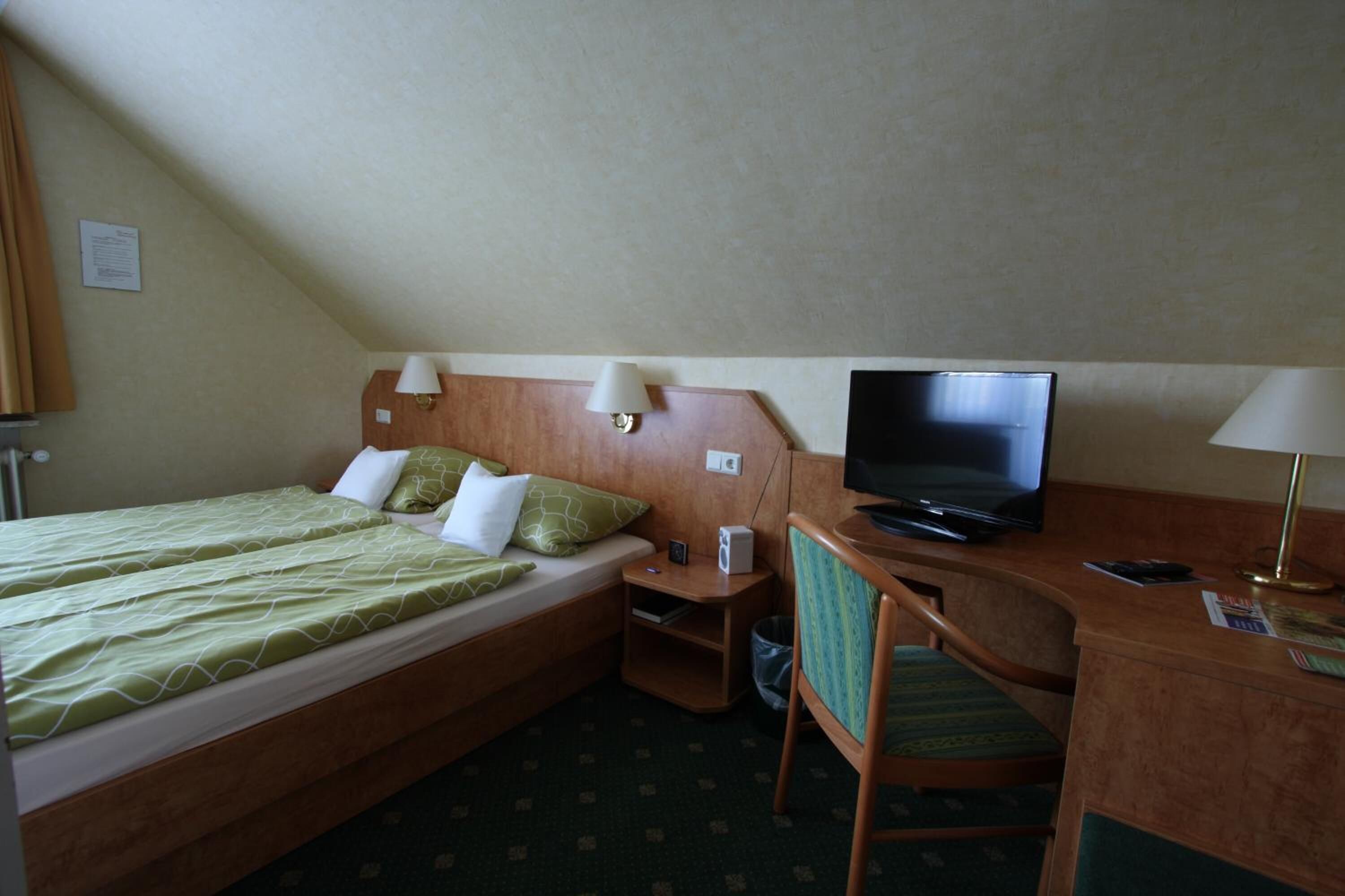 A hotel room with two beds, a desk with a television, and a chair.