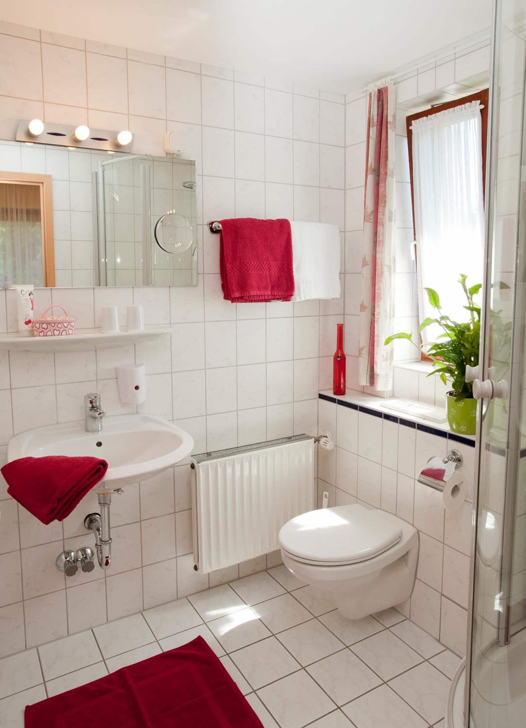 Une salle de bain moderne avec un lavabo blanc, des toilettes, une douche en verre et un miroir avec éclairage intégré.