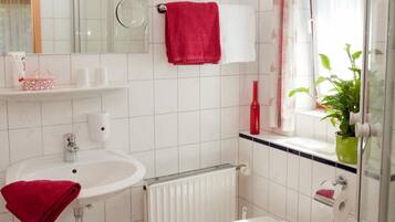 Une salle de bain moderne avec un lavabo blanc, des toilettes, une douche en verre et un miroir avec éclairage intégré.
