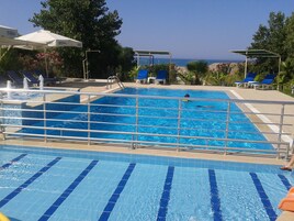 Una piscina al aire libre, una piscina con cascada, sombrillas