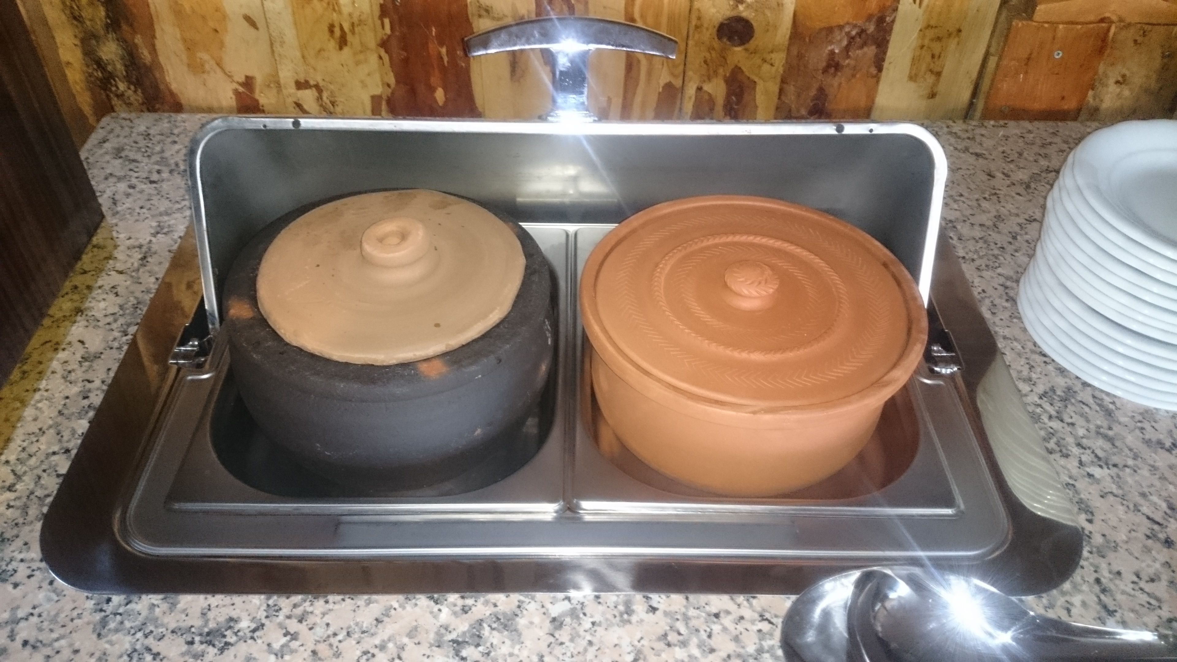 A kitchen sink with two containers, one black and one terracotta, on a granite countertop.