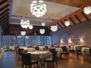 A restaurant with multiple tables and chairs, modern pendant lighting, and a decorative wall with lights. - Chalet Greenwood (Zbunin)