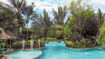 Un resort tropical con una piscina central rodeada de exuberante vegetación y palmeras.