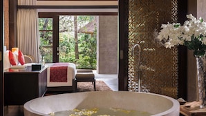A spacious room with a large bathtub, a bed, and a view of lush greenery outside. - Royal Tulip Springhill Resort Jimbaran (Jimbaran)
