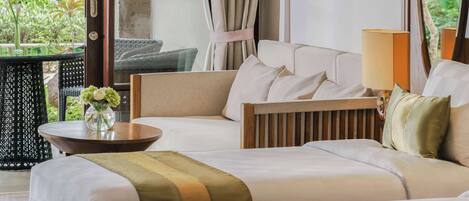 Habitación de hotel con sofá cama, una pequeña mesa con un florero y vistas a zonas verdes.