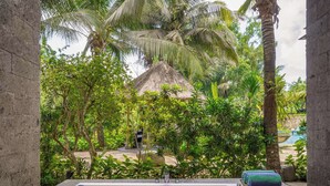 A spa area with a bathtub filled with pink flower petals, surrounded by lush greenery and a thatched-roof structure. - Royal Tulip Springhill Resort Jimbaran (Jimbaran)