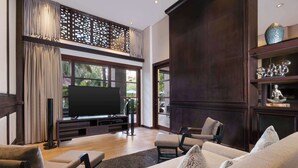 A spacious living room with a large flat-screen TV, comfortable seating, and a decorative shelf. - Royal Tulip Springhill Resort Jimbaran (Jimbaran)