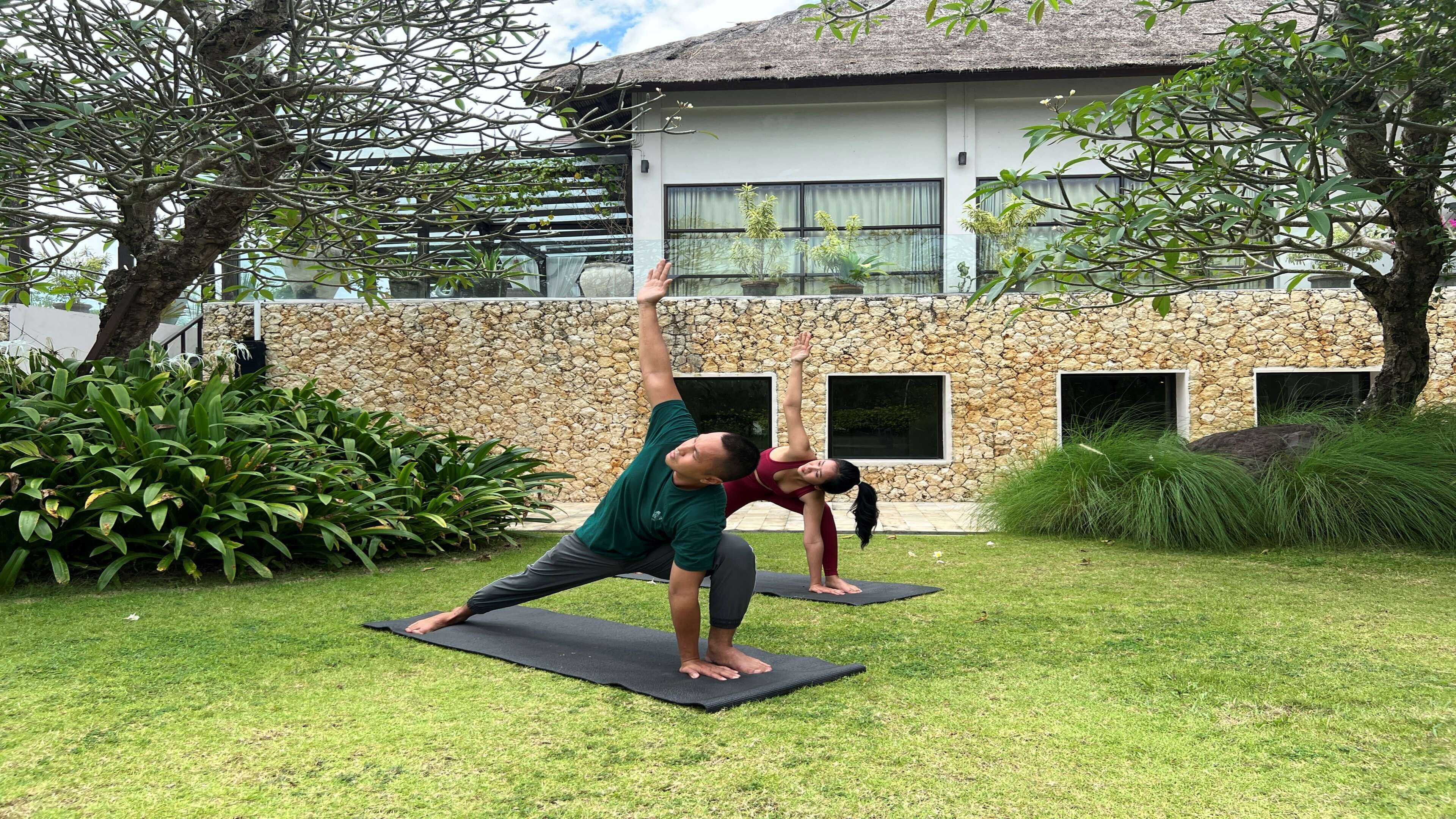 Due persone che praticano yoga all'aperto su tappetini.