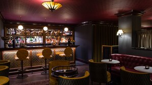 Una zona de bar con mostrador, taburetes y un sofá de cuero rojo.