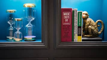 A shelf with books, a golden monkey statue, and hourglasses.