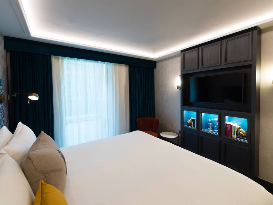 Habitación de hotel con una cama grande, una silla, un escritorio y un mueble empotrado para la televisión.