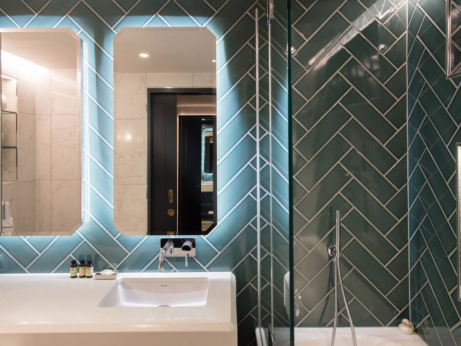 Un baño moderno con un espejo grande, un lavabo blanco y una zona de ducha.