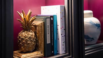 A shelf with books and a pineapple ornament.