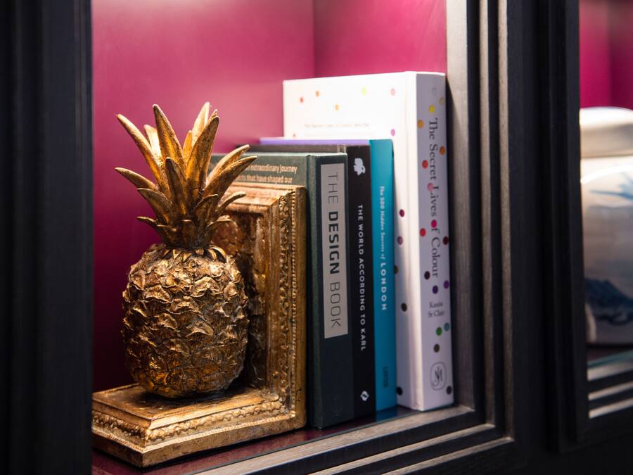 A shelf with books and a pineapple ornament.