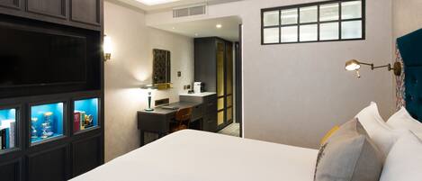 A hotel room with a large bed, a desk with a chair, a television, and a window.