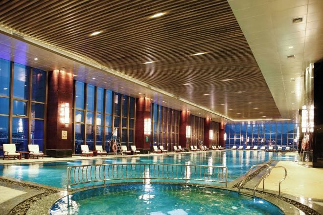 Una amplia piscina interior con techo de madera y ventanas grandes.