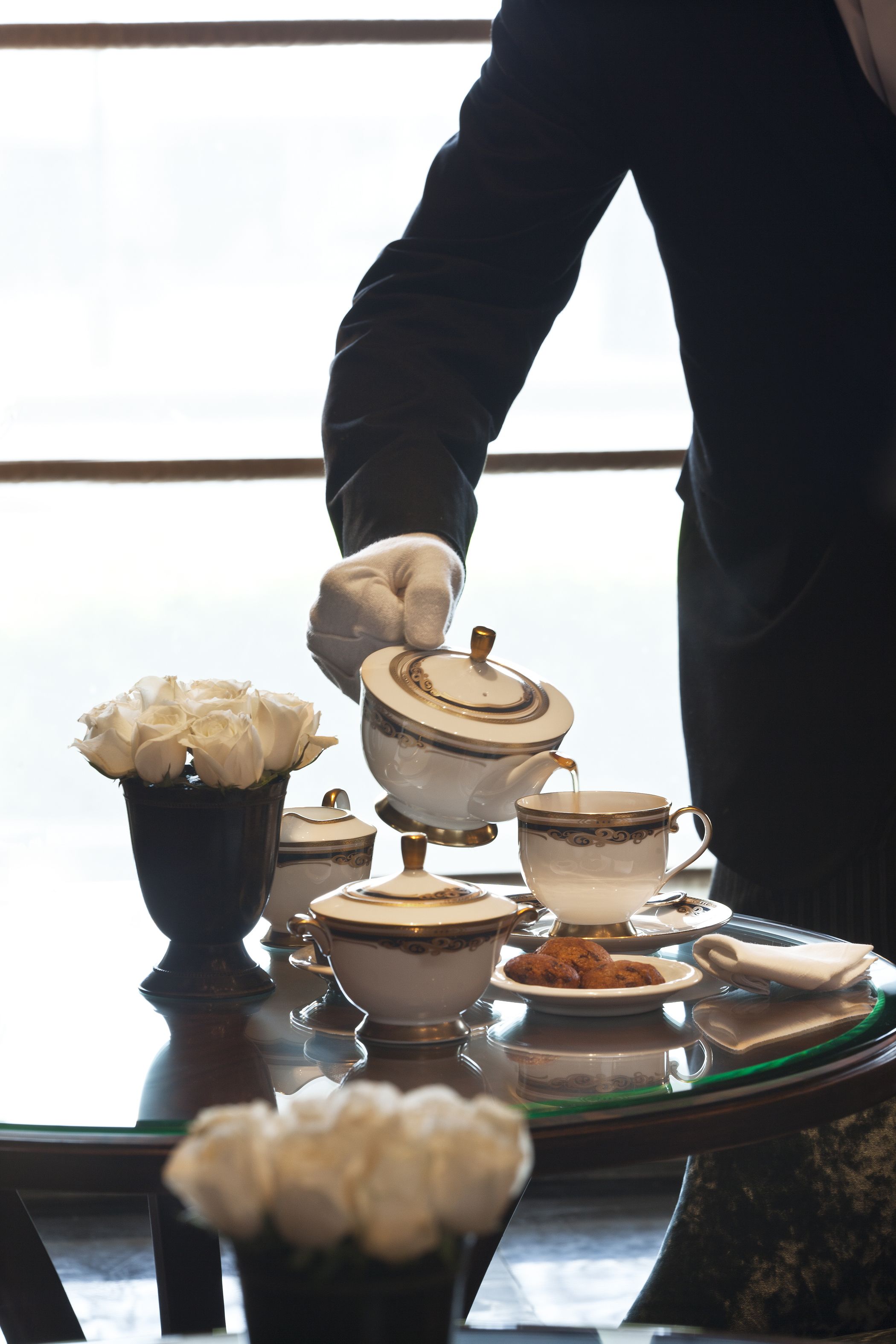 Una mesa servida con servicio de té, que incluye una tetera, tazas y un plato de galletas.