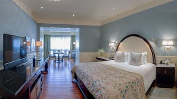 A hotel room with a large bed, a TV, a desk with a chair, and a view of the outdoors.